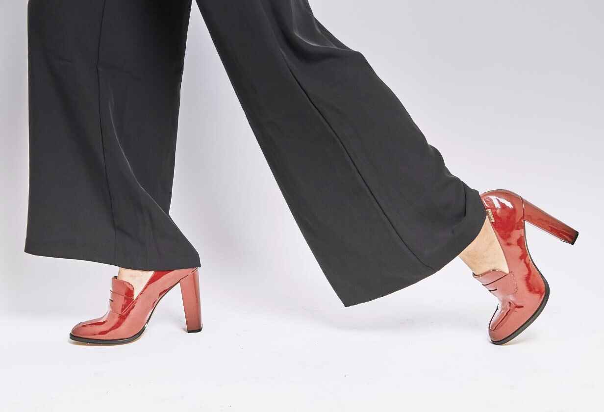 femeie cu pantofi rosii lacuiti cu toc inalt gros si pantaloni negrii largi