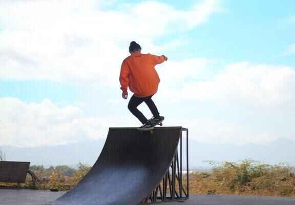 barbat cu hanorac portocaliu pe skateboard