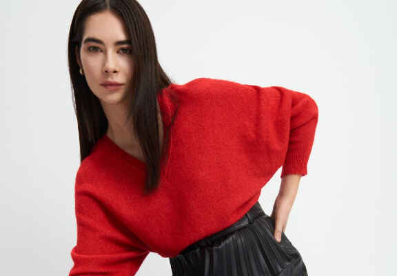 femeie cu pulover oversize rosu si fusta neagra plisata