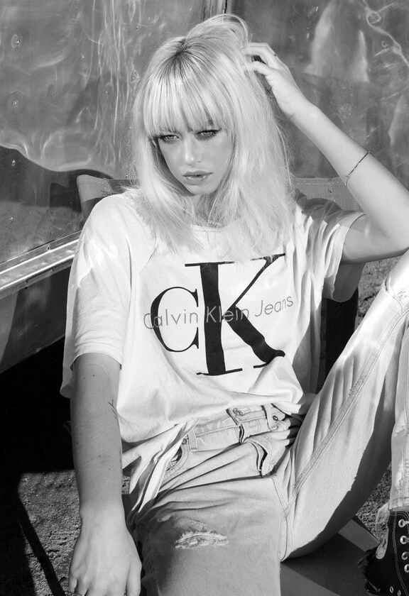 femeie cu tricou alb cu maneci scurte si inscriptie neagra Calvin Klein
